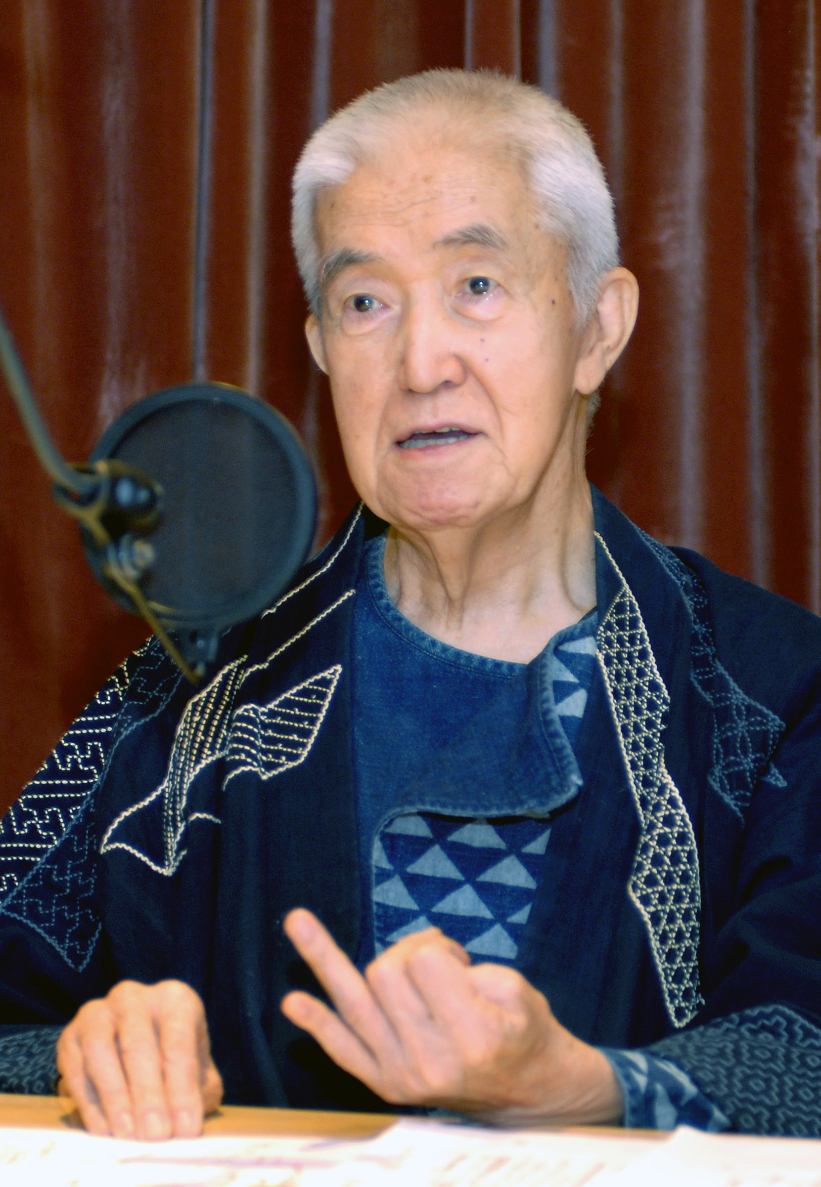 藍色の和装姿でラジオのマイクに向かう永六輔
